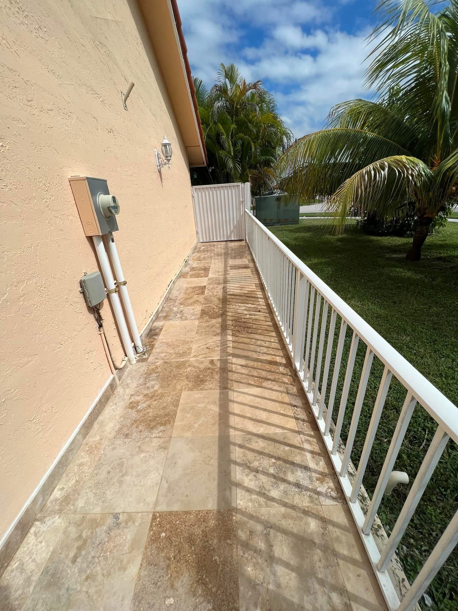 Pasillo exterior con piso de tile y baranda blanca