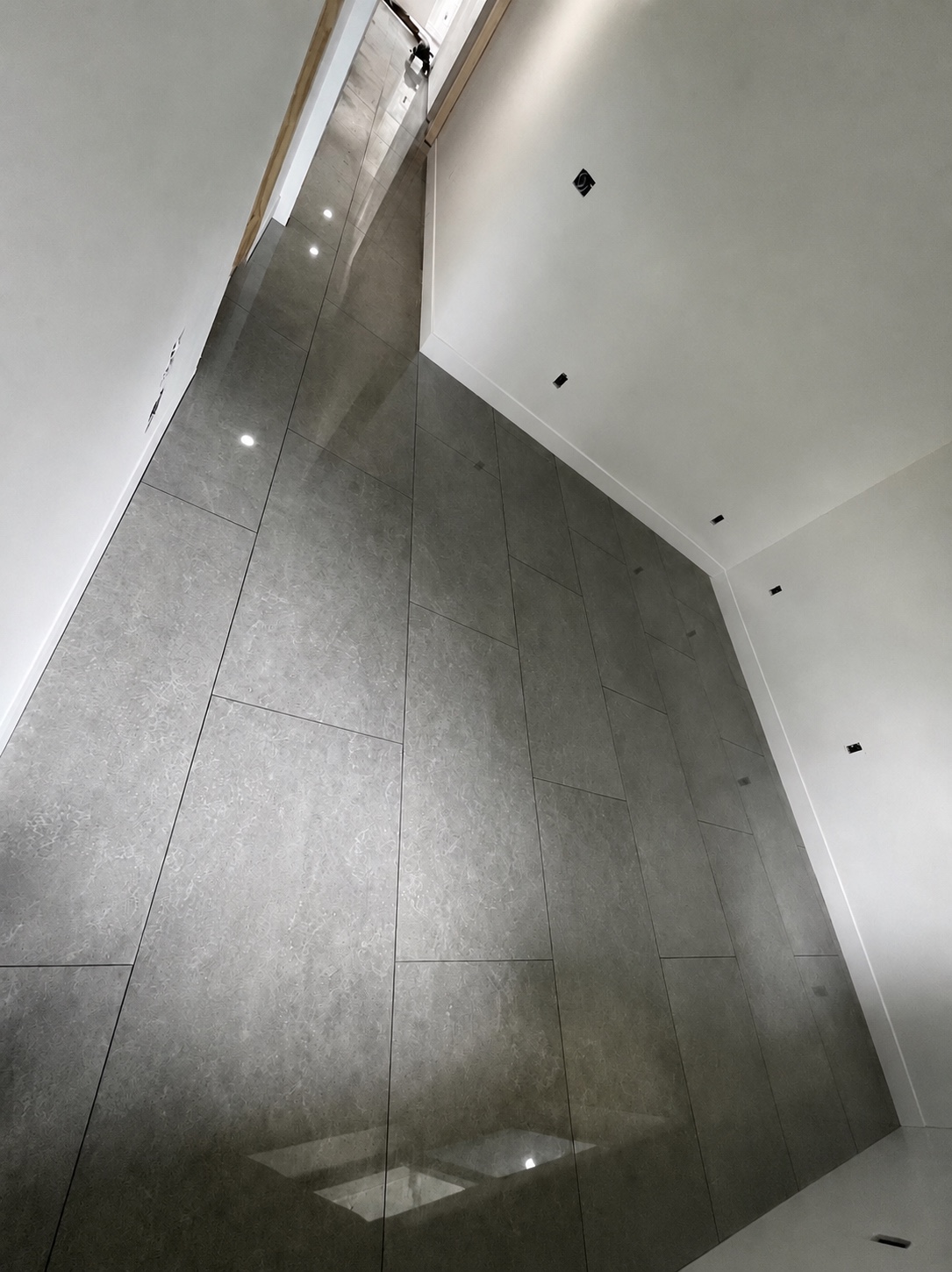 Piso gris brillante con piezas de gran formato y zócalos blancos