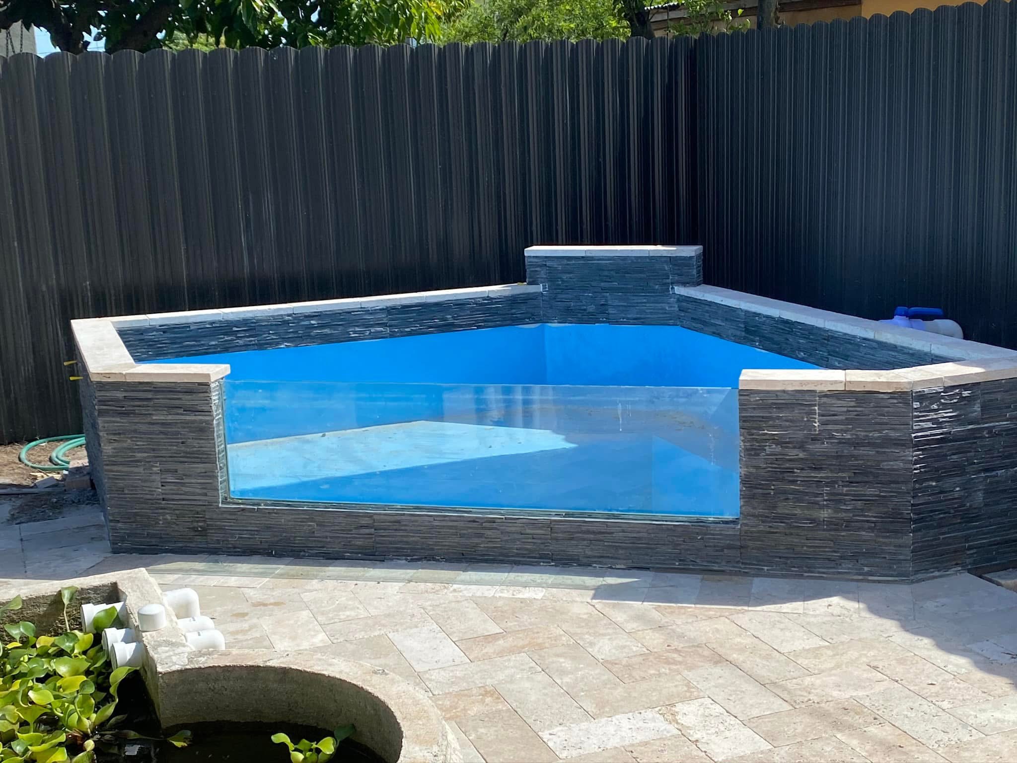 Piscina elevada con frente de cristal y revestimiento de piedra