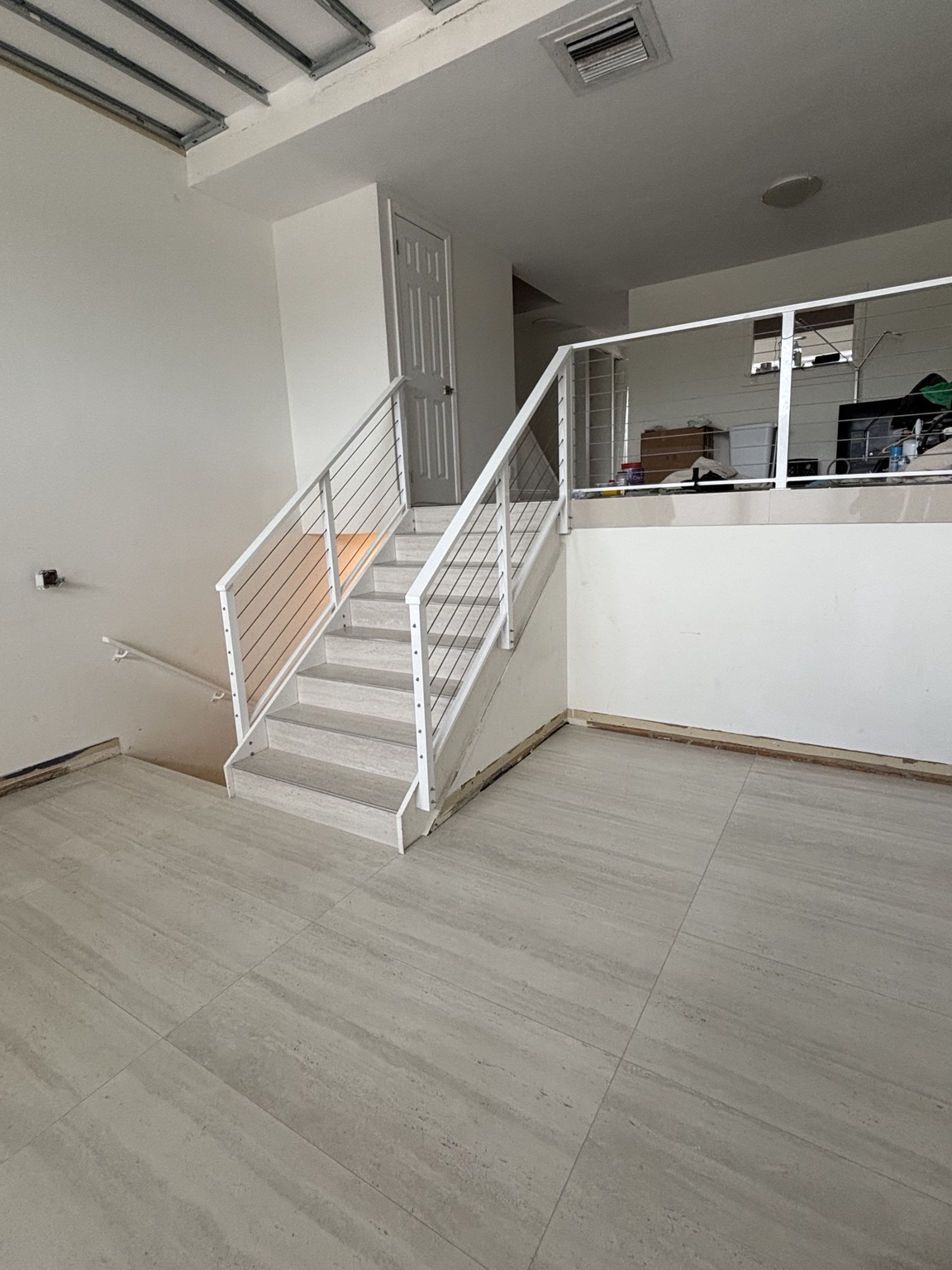 Escalera revestida y piso claro junto a barandas metálicas