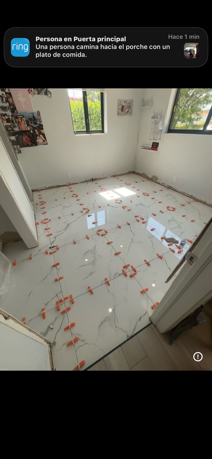 Piso blanco con vetas grises y separadores durante instalación