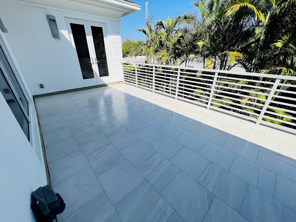 Piso claro de balcón junto a puertas blancas y palmeras