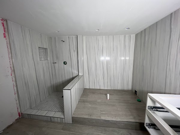 Baño en remodelación con revestimiento de vetas verticales y ducha con media pared