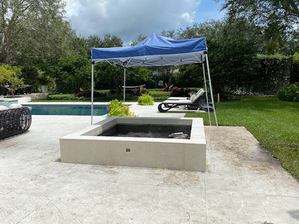 Estructura cuadrada revestida de piezas claras en patio junto a piscina