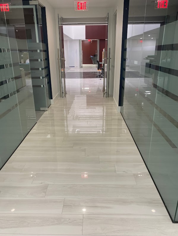 Pasillo de oficinas con piso claro brillante y divisiones de cristal