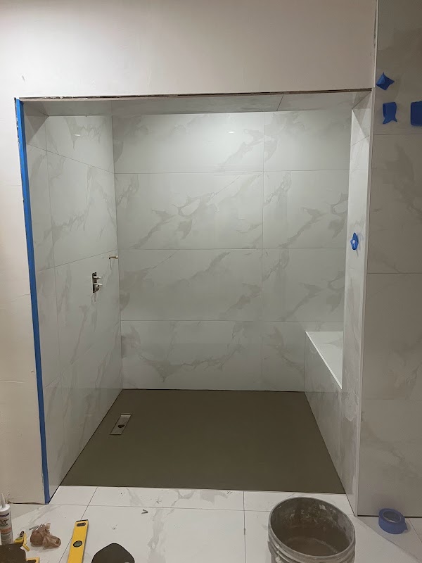 Ducha en construcción con banco y paredes de acabado marmoleado blanco