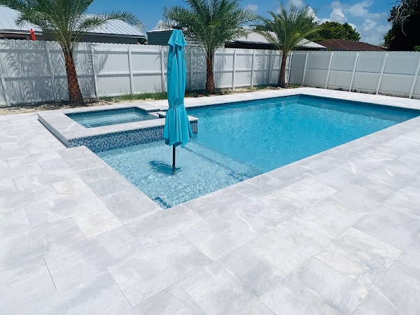 Piscina con spa y piso exterior claro alrededor