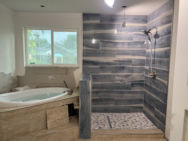 Ducha con revestimiento de apariencia madera oscura junto a bañera