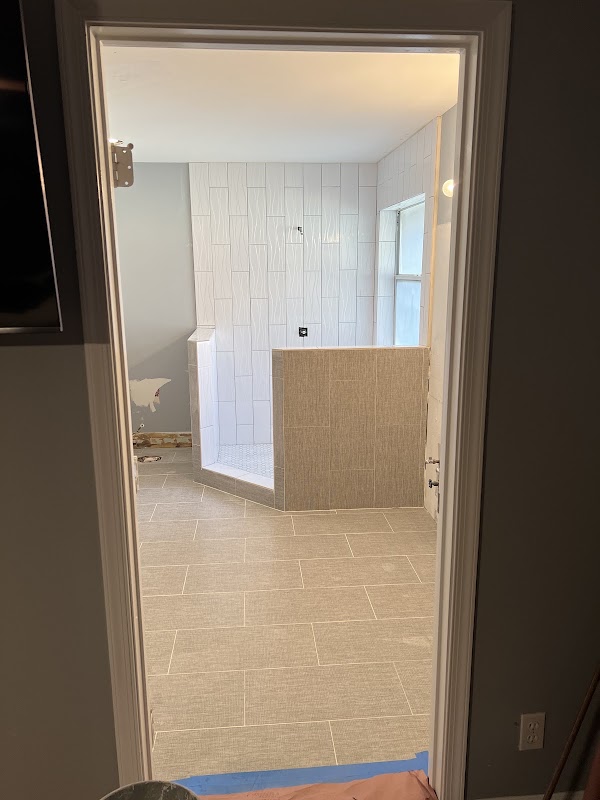 Baño en remodelación con piso beige y ducha de azulejos blancos