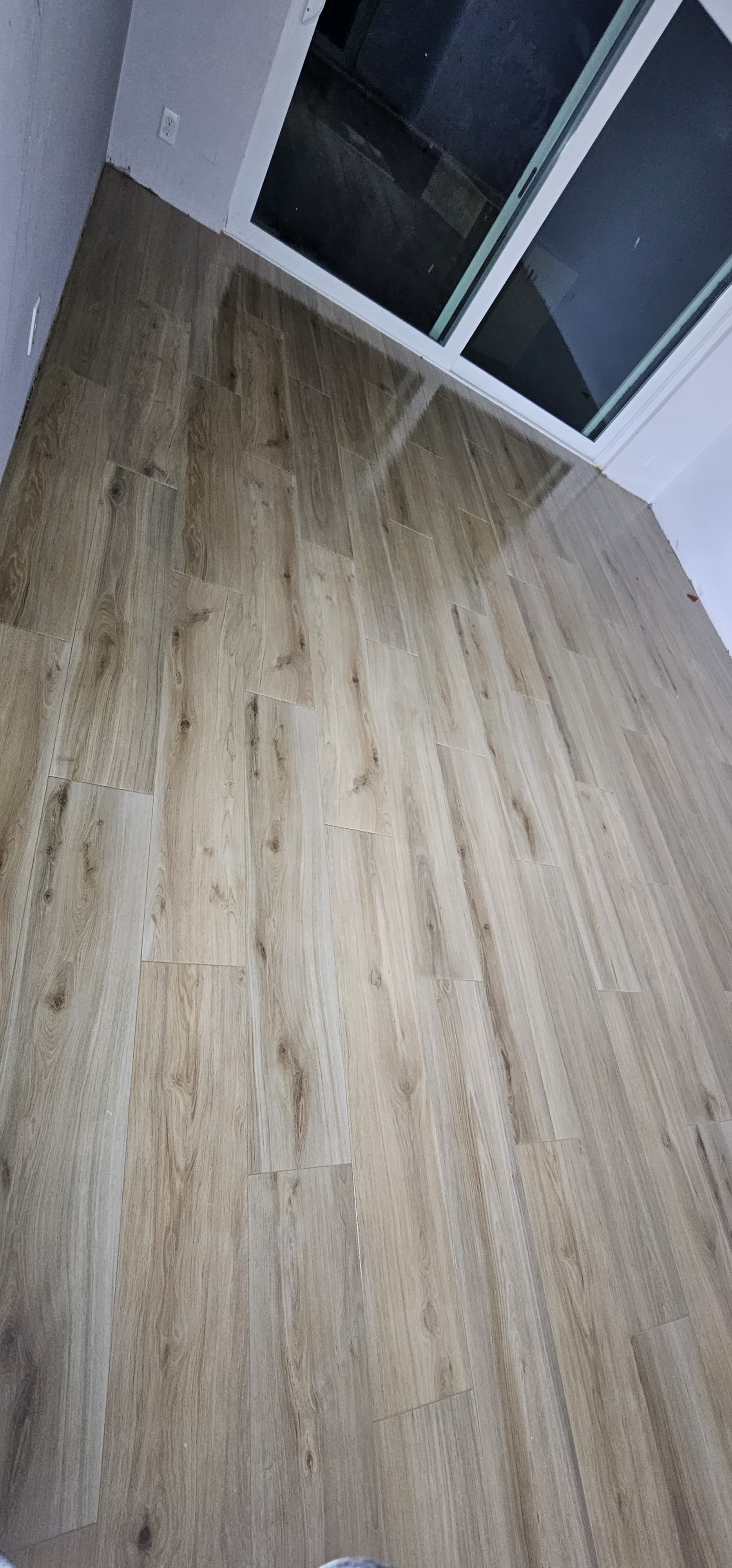 Detalle de piso de apariencia madera junto a puerta de cristal