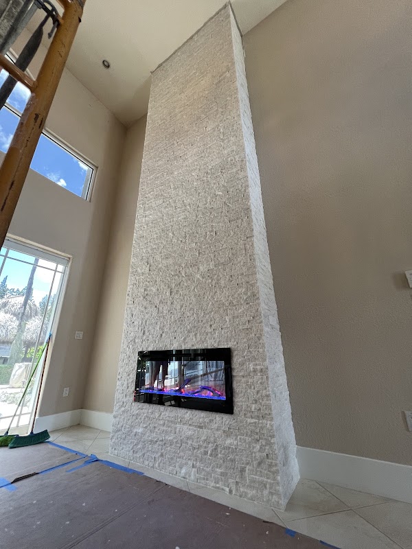 Chimenea alta revestida de piedra blanca junto a ventanales