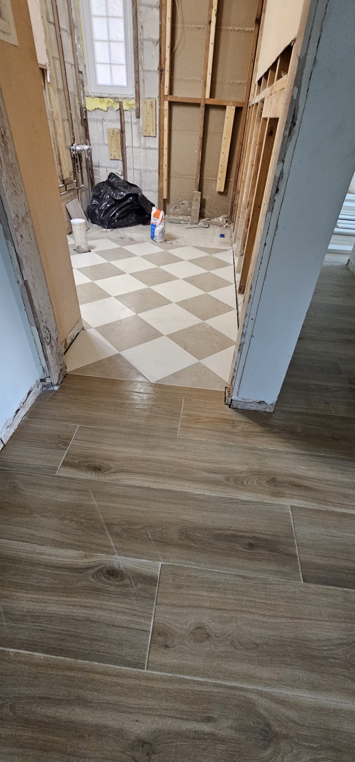 Piso con apariencia madera junto a entrada de baño con piso de diseño geométrico durante remodelación