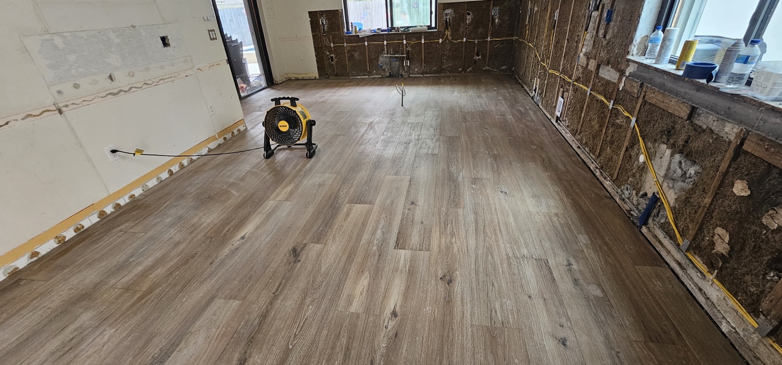 Vista amplia de piso con apariencia madera en cocina con paredes abiertas durante remodelación